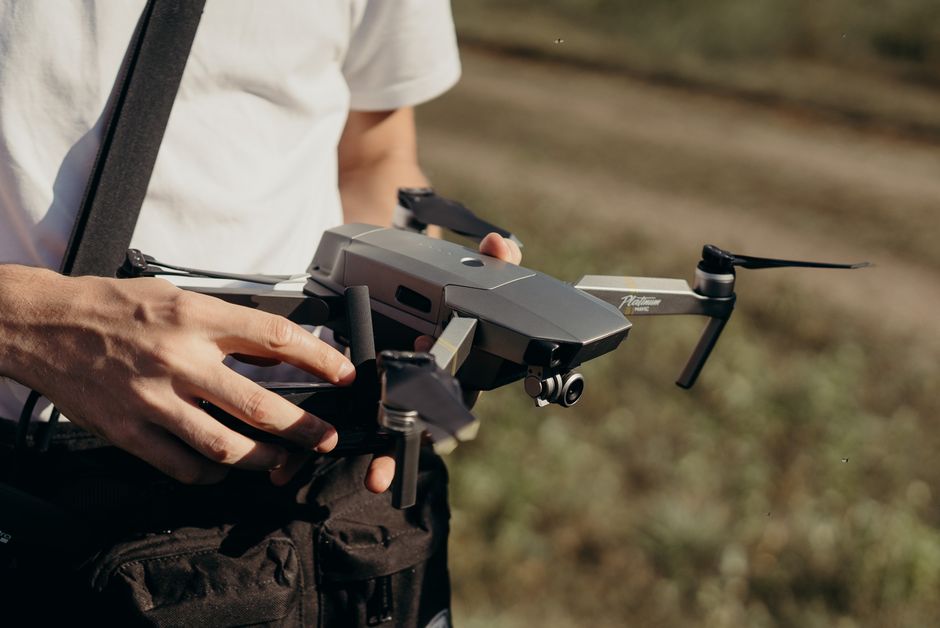 Ekipman gerektiren yan iş fikirlerinden drone çekimi: kumandayla açık havada drone uçuran bir adam